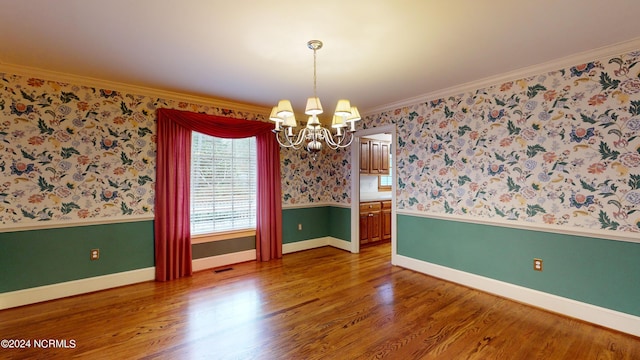 unfurnished room with ornamental molding, dark hardwood / wood-style flooring, and an inviting chandelier