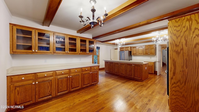 kitchen featuring decorative light fixtures, an inviting chandelier, light hardwood / wood-style floors, beam ceiling, and stainless steel refrigerator