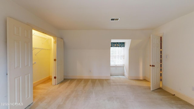 unfurnished bedroom featuring a walk in closet, light carpet, and a closet