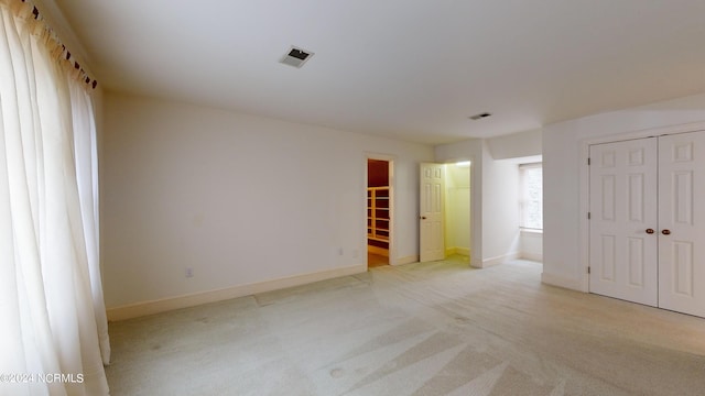 unfurnished bedroom with a closet, ensuite bath, and light colored carpet