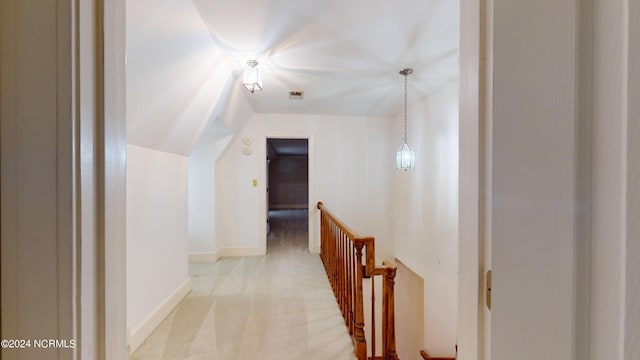 hall featuring vaulted ceiling and light colored carpet