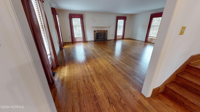 unfurnished living room with plenty of natural light, dark hardwood / wood-style flooring, and ornamental molding