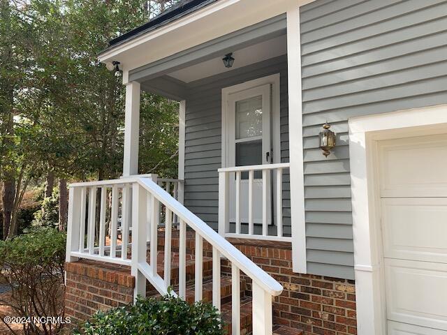 doorway to property with covered porch and a garage