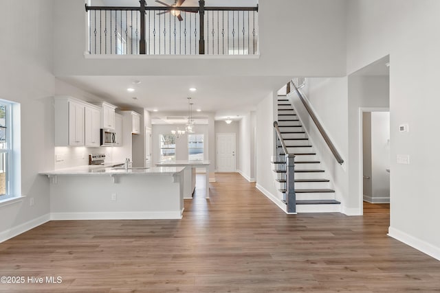 kitchen with stainless steel appliances, dark wood-type flooring, white cabinets, and a kitchen breakfast bar