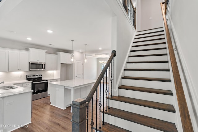 kitchen with light stone counters, decorative light fixtures, appliances with stainless steel finishes, a kitchen island, and white cabinets