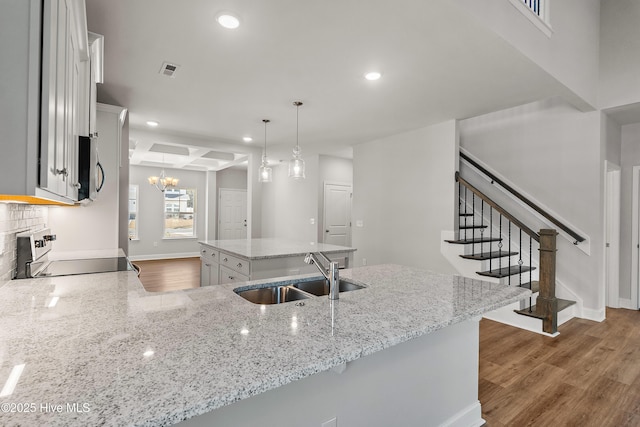 kitchen with sink, range, white cabinetry, hanging light fixtures, and a kitchen island