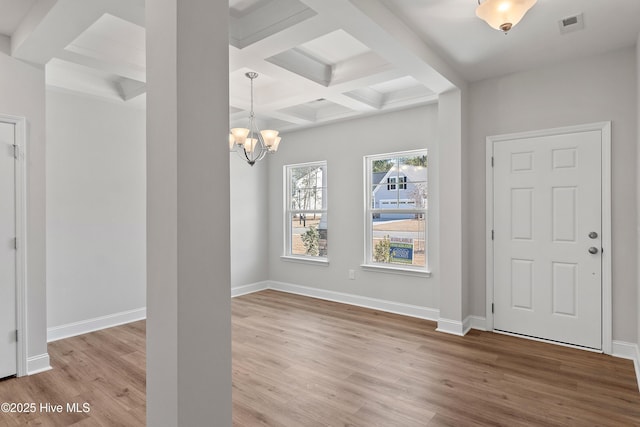 foyer entrance with beam ceiling, coffered ceiling, an inviting chandelier, and light wood-type flooring