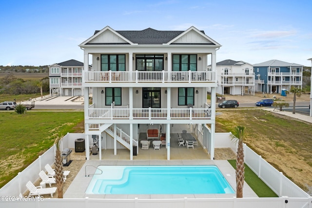 rear view of house featuring a balcony, a fenced in pool, and a patio area