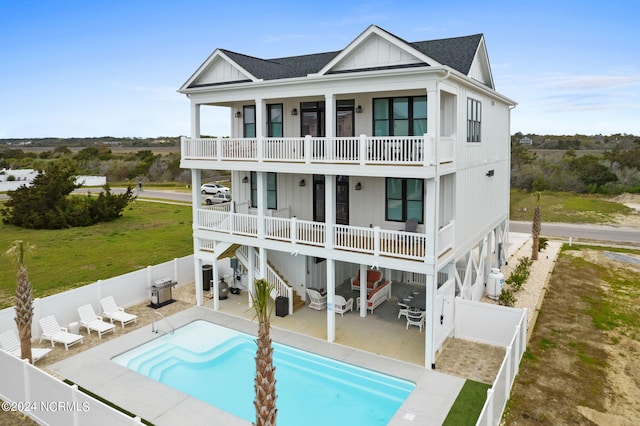 back of property with a patio, a balcony, and a fenced in pool