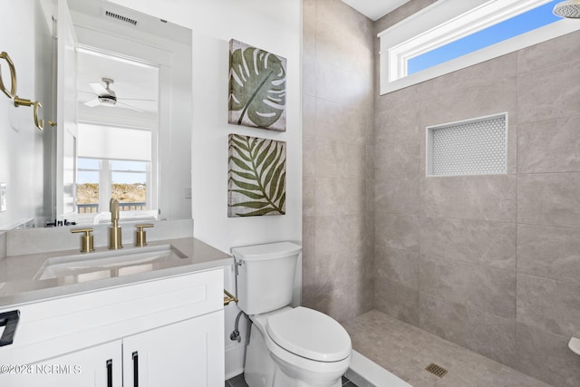 bathroom featuring toilet, vanity with extensive cabinet space, ceiling fan, and a wealth of natural light