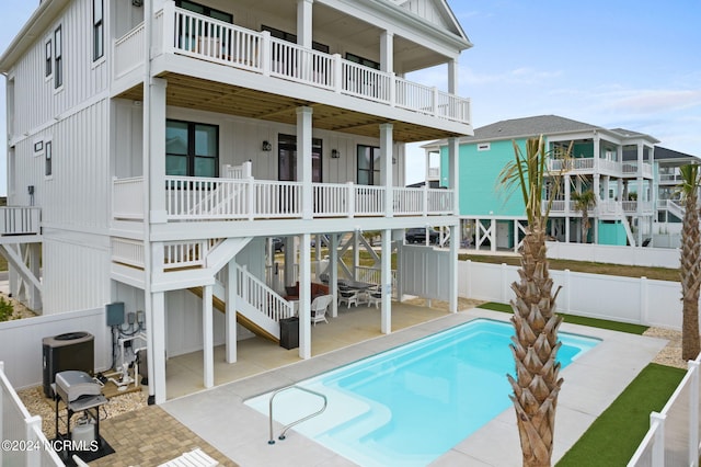 rear view of house featuring a fenced in pool, a balcony, and a patio