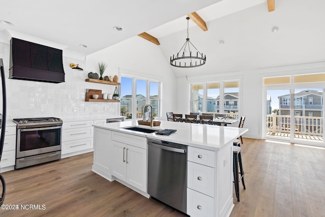 kitchen featuring sink, hardwood / wood-style floors, white cabinets, appliances with stainless steel finishes, and vaulted ceiling with beams