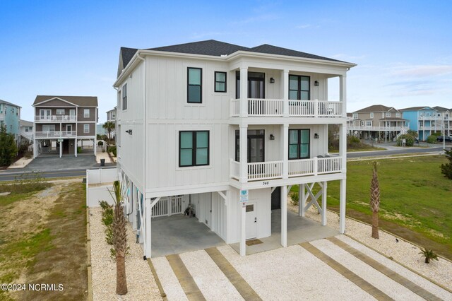 raised beach house featuring a balcony and a carport