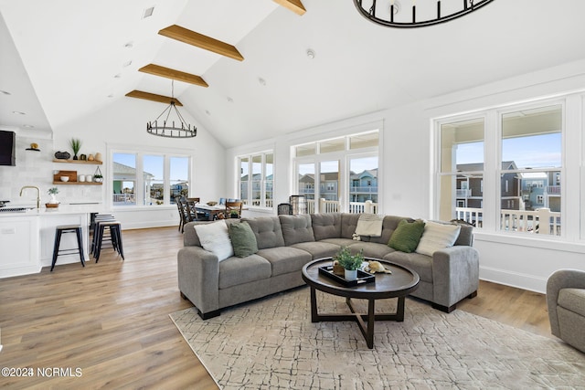 living room with sink, high vaulted ceiling, light wood-type flooring, and beamed ceiling