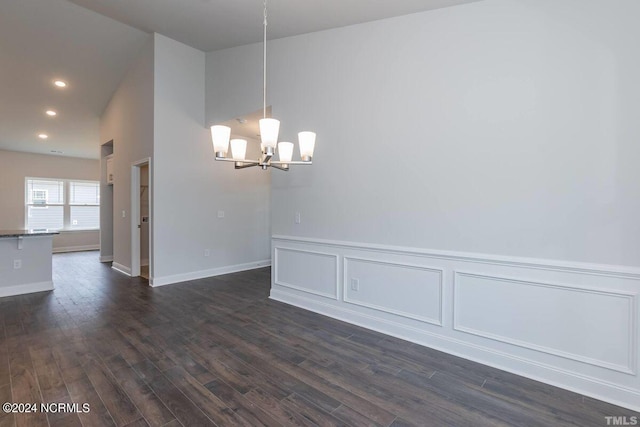 unfurnished dining area with a wainscoted wall, a notable chandelier, recessed lighting, a decorative wall, and dark wood-type flooring