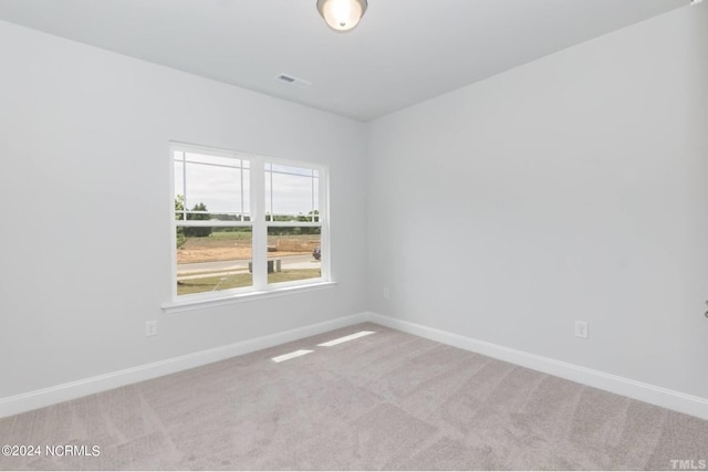 unfurnished room featuring light colored carpet, visible vents, and baseboards