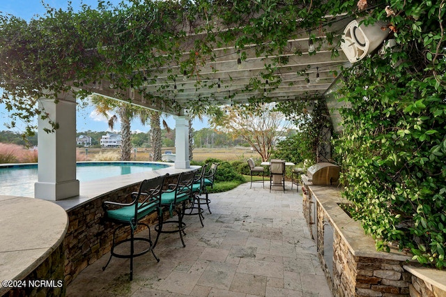 view of terrace with an outdoor bar, a pergola, area for grilling, and a fenced in pool