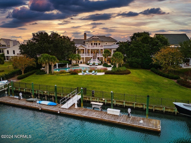 dock area with a lawn, a balcony, and a water view