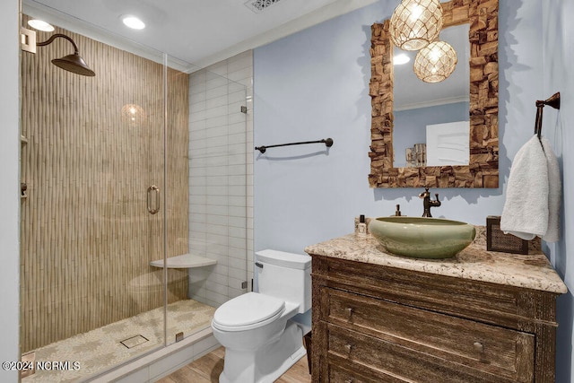 bathroom featuring toilet, ornamental molding, a shower with door, wood-type flooring, and vanity