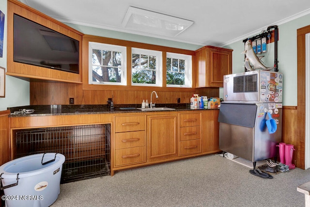 kitchen featuring dark stone counters, crown molding, sink, and light colored carpet