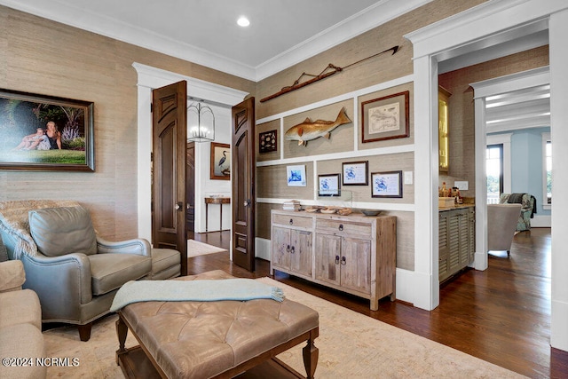 living room featuring dark hardwood / wood-style floors, an inviting chandelier, and ornamental molding