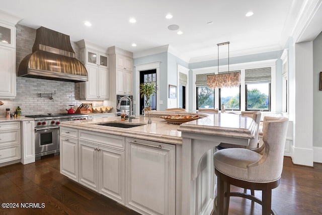 kitchen with wall chimney exhaust hood, designer range, dark hardwood / wood-style flooring, and light stone counters