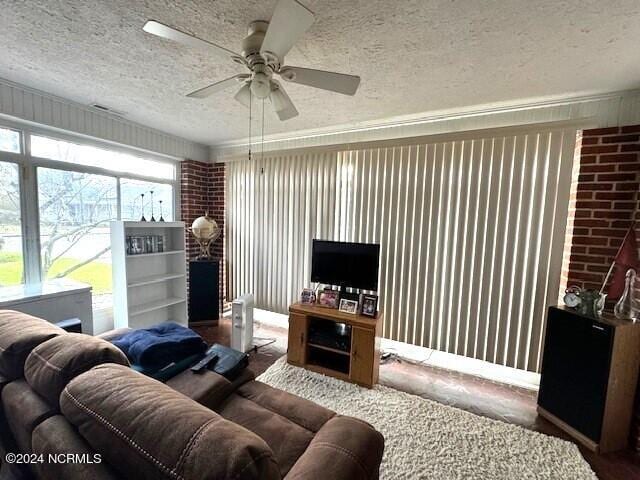 living room with brick wall, ceiling fan, and a textured ceiling