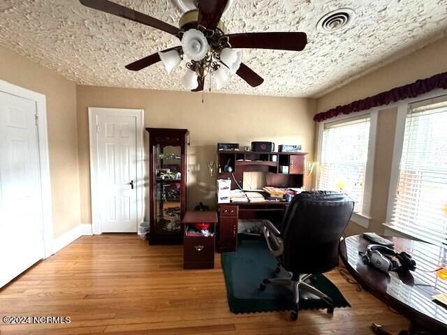 home office with light hardwood / wood-style floors, a textured ceiling, and ceiling fan