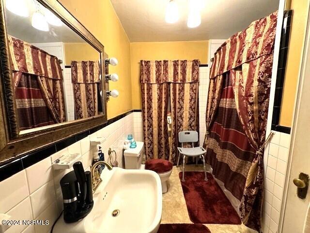 bathroom featuring backsplash, tile walls, tile floors, and toilet