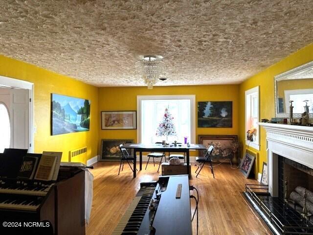 interior space featuring a notable chandelier, radiator, light wood-type flooring, and a textured ceiling