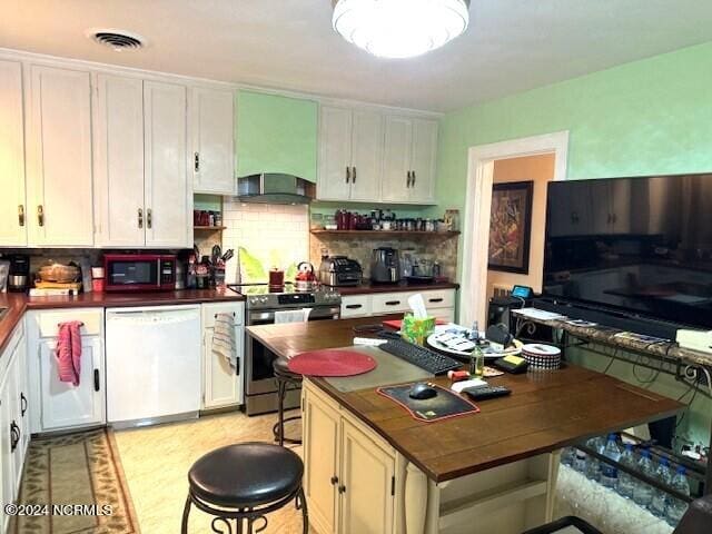 kitchen featuring white dishwasher, wall chimney range hood, stainless steel electric range oven, white cabinetry, and backsplash