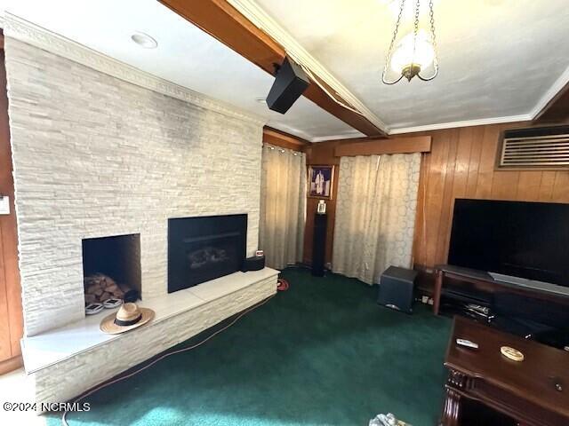 unfurnished living room featuring an inviting chandelier, wood walls, crown molding, dark colored carpet, and a fireplace