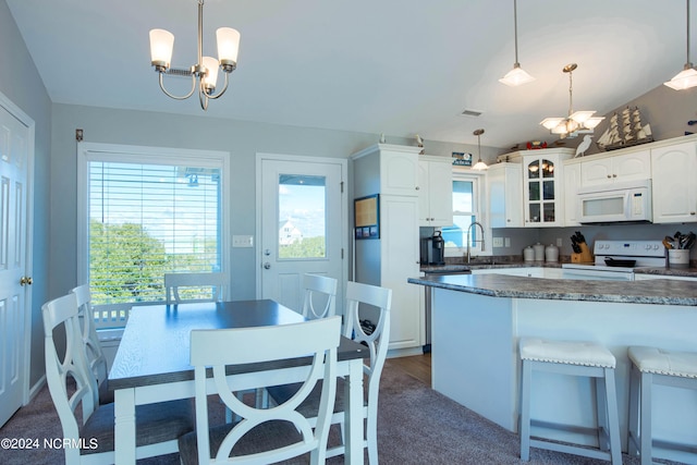 kitchen featuring white appliances, sink, pendant lighting, a notable chandelier, and white cabinets