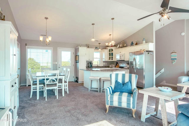 kitchen featuring stainless steel fridge, vaulted ceiling, white cabinetry, and pendant lighting