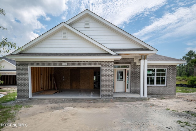 view of front of property featuring an attached garage, roof with shingles, and brick siding