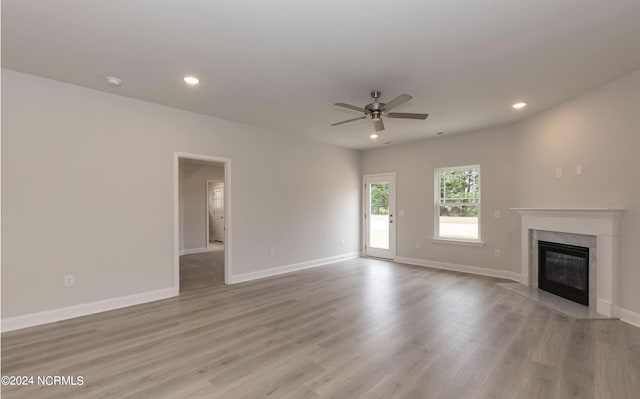 unfurnished living room with recessed lighting, a ceiling fan, a high end fireplace, wood finished floors, and baseboards