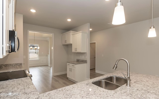 kitchen featuring white cabinetry, stainless steel microwave, light stone counters, and a sink