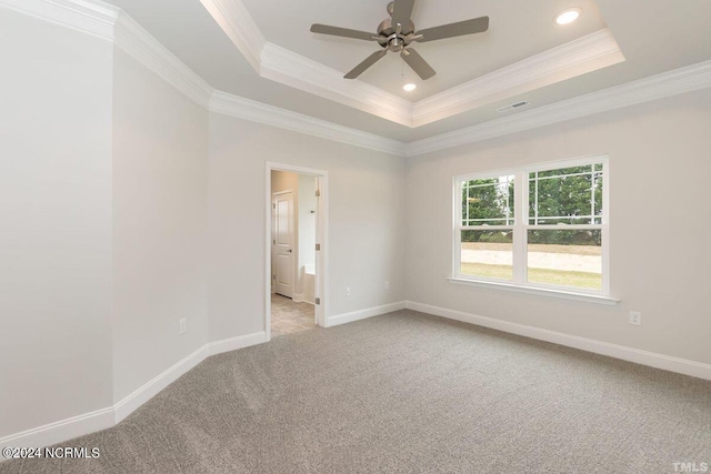 carpeted spare room featuring ornamental molding, a raised ceiling, and baseboards