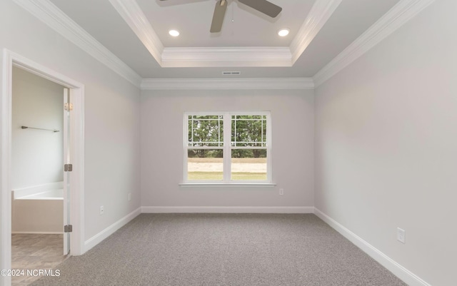 empty room with baseboards, visible vents, a tray ceiling, crown molding, and carpet flooring