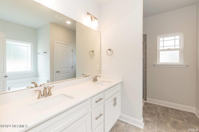 bathroom featuring plenty of natural light, a sink, and baseboards