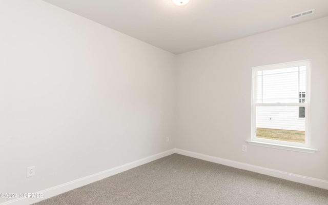 spare room featuring light carpet, visible vents, and baseboards