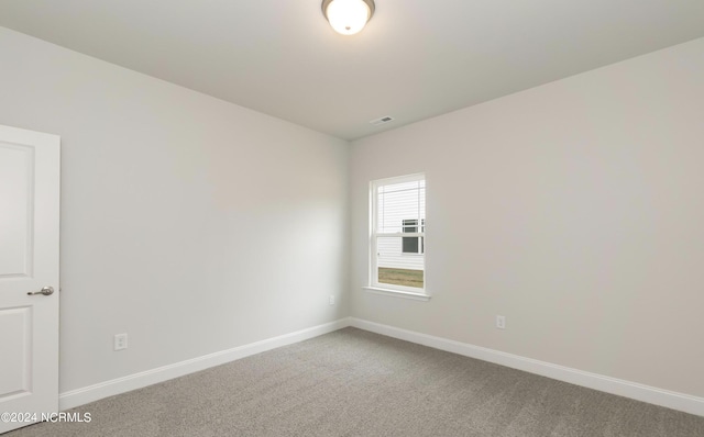 spare room featuring carpet, visible vents, and baseboards