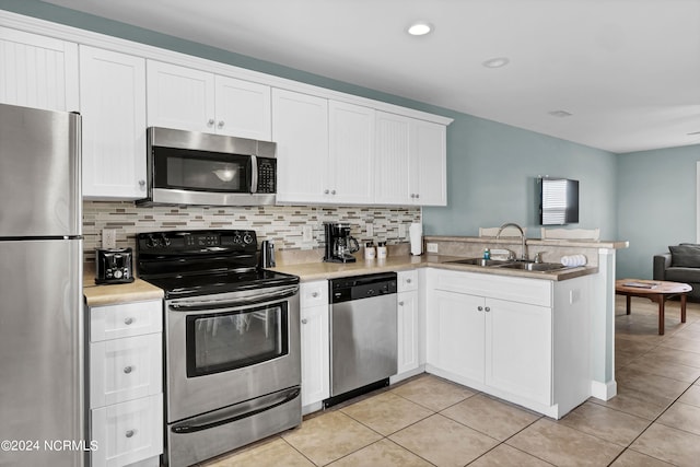 kitchen with backsplash, kitchen peninsula, white cabinets, and appliances with stainless steel finishes