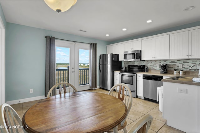 kitchen with backsplash, stainless steel appliances, white cabinetry, and sink