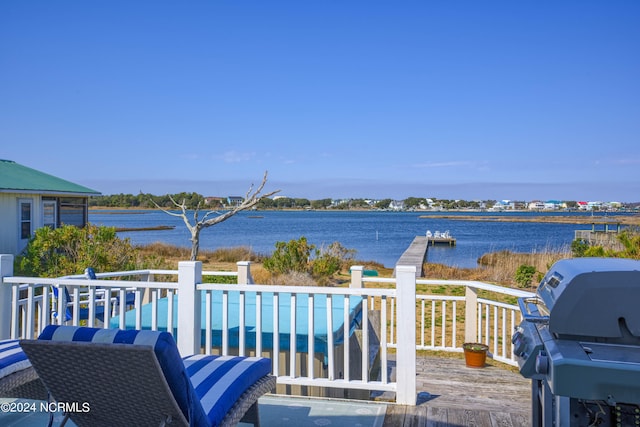 wooden deck featuring area for grilling, a swimming pool, and a water view