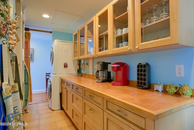 kitchen with stacked washer / drying machine, light brown cabinetry, and light tile patterned floors