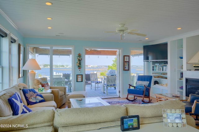 living room with ornamental molding, a water view, ceiling fan, and built in features