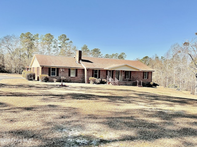 rear view of property with covered porch and a yard