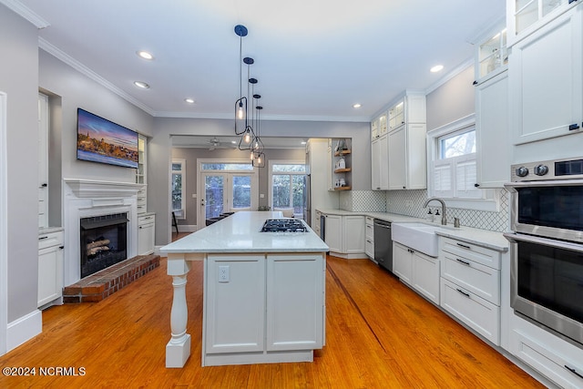 kitchen featuring white cabinetry, a brick fireplace, a kitchen island, light wood-type flooring, and a wealth of natural light