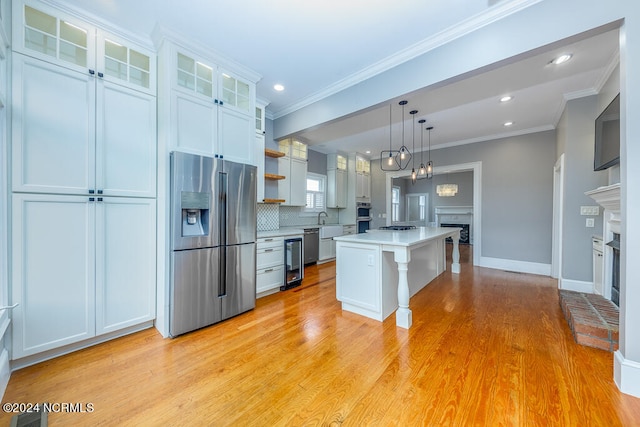 kitchen with light hardwood / wood-style floors, a center island, white cabinets, a fireplace, and stainless steel appliances